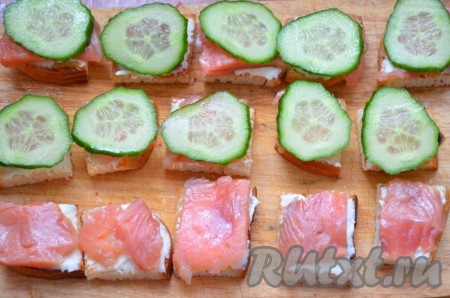 Выложить рыбку на сыр.&nbsp;Огурец нарезать на тонкие кружочки, выложить на рыбу.