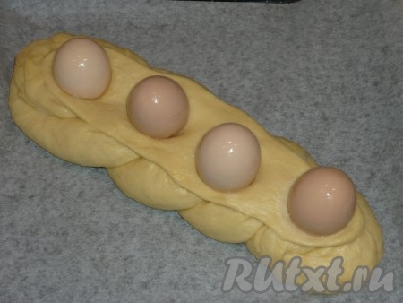 Четвёртую часть теста отдельно раскатываем и выкладываем на косичку. Четыре яйца тщательно моем с содой, смазываем яйца растительным маслом и усаживаем сверху на верхний пласт (как на фото).