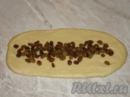 Когда тесто подойдёт, разделяем его на 4 равные части. Одну часть откладываем в сторону, а три части раскатываем, чтобы получились пласты теста одинаковой длины. На каждый пласт кладём свою начинку: на один -&nbsp; сахар с молотой корицей, на второй пласт - изюм, а на третий - измельчённые орехи.
