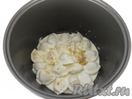 Залить сметанной смесью пельмени, посолить и поперчить.