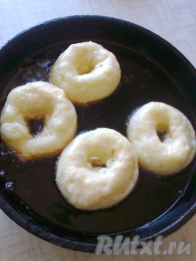 В сковороде с высокими бортиками или в сотейнике на сильном огне разогреть растительное масло, убавить огонь до среднего и обжарить пончики с двух сторон до золотистого цвета.