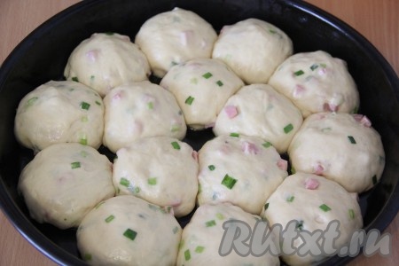 Тесто разделить на 10-12 частей. Руки перед формированием булочек смазать растительным маслом. Сформировать круглые булочки и выложить их в форму для выпечки, смазанную растительным маслом, накрыть полотенцем и поставить в тепло на 30-40 минут.