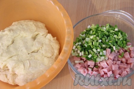 Вначале перемешивать тесто столовой ложкой, а когда оно начнёт собираться в ком, продолжать вымешивать его руками. Частями добавляя оставшееся молоко, хорошо вмешивая его, замесить мягкое, слегка липнущее к рукам тесто. Именно добавлением молока в этом рецепте регулируется консистенция теста, как только тесто стало чуть липнущим, но при этом приятным в работе, значит больше не нужно добавлять молоко. В общей сложности вымешивать тесто руками нужно минут 7. Колбасу нарезать на мелкие кубики. Зелень (у меня - зелёный лук, но можно взять и укроп или петрушку), если будете добавлять в эту выпечку, нужно промыть водой, обсушить, мелко нарезать.