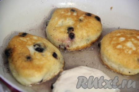 Сковороду для выпекания хорошо разогреть, добавить растительное масло (масла не жалеть!). Выкладывать по 1 столовой ложке теста, формируя оладушки. Жарить оладьи с черникой с двух сторон на среднем огне до золотистого цвета. Готовые оладушки переложить на тарелку. Таким образом пожарить все оладьи.