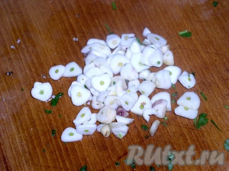 Нарезать чеснок и положить в ту же емкость вместе с зеленью.
