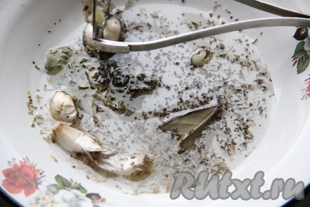 Зубчики чеснока, не очищая от кожуры, тщательно вымыть. Отдельно смешать 3 столовых ложки растительного масла, специи, уксус, перемешать, добавить зубчики чеснока в кожуре и лавровые листья. Слегка примять чеснок толкушкой.