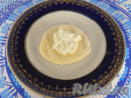 Тесто немного обмять, разделить на части, скатать колбаски и порезать кусочками. Сформировать лепешки. В середину лепешки поместить по ложке творожной массы.