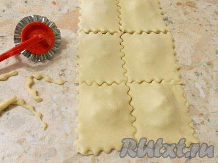 Накрыть второй половиной теста и специальным ножом обрезать все края, придавая форму равиоли.