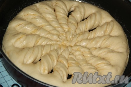 Противень для выпекания смазать растительным маслом. Аккуратно переложить заготовку для пирога в форму. Сделать 8 надрезов от края до края, острым ножом, не прорезая край пирога. У нас получится 16 равных частей треугольной формы. Затем свернуть треугольники в плотные жгутики. Получившийся пирог поставить в тёплое место для расстойки на 20-30 минут.