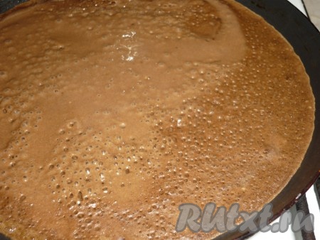 Немного смазать сковороду растительным маслом, разогреть, уменьшить огонь до среднего, а затем влить половник теста, равномерно распределяя тесто по дну сковороды. Когда блин покроется сверху пузырьками и поджарится с нижней стороны, перевернуть его и жарить до подрумянивания с другой стороны. Готовый ароматный шоколадно-кофейный блин переложить на тарелку. Периодически перемешивая блинное тесто и смазывая сковороду маслом по мере необходимости, постепенно пожарить все блины.