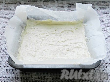 Форму для выпечки (я взяла форму размером 20 на 20 сантиметров) застелить пергаментной бумагой. Немного смазать бумагу сливочным или растительным маслом. Выложить творожно-манную массу и разровнять.