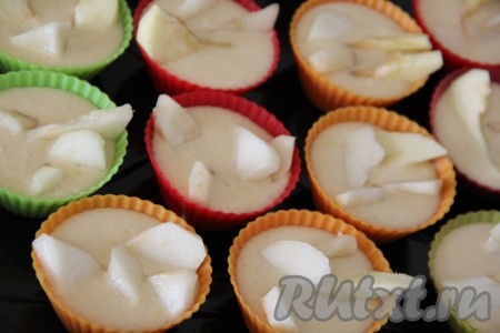 Разложить тесто по формочкам, заполняя их на 1/2 объёма. Я использовала силиконовые формочки. Выложить кусочки груши поверх теста и слегка утопить их в тесто. Духовку заранее разогреть до 180 градусов.