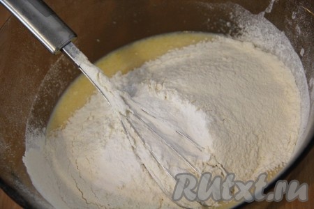 Далее всыпать просеянную муку и разрыхлитель. Всё перемешать до однородности. Консистенция теста должна быть не густой, слегка комковатой.