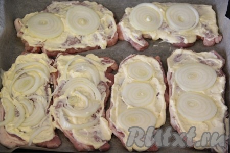 Смазать получившимся соусом кусочки свинины. Лук почистить и порезать на тонкие кольца. Выложить луковые кольца на свинину поверх соуса.
