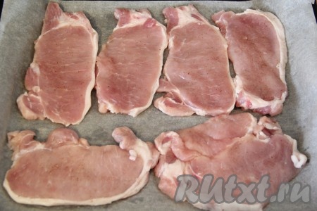 Свинину порезать на порционные кусочки, не тонко. Слегка отбить кусочки свинины. Посолить и поперчить по вкусу. Противень для запекания выстелить пергаментом. Выложить кусочки свинины на пергамент.