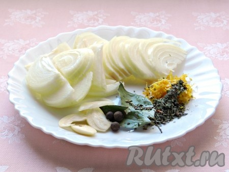 Подготовить необходимые специи. Очистить лук и чеснок. Лук нарезать полукольцами, чеснок - пластинками. Лимон тщательно вымыть, с половины лимона снять цедру, не затрагивая находящийся под ней белый слой.