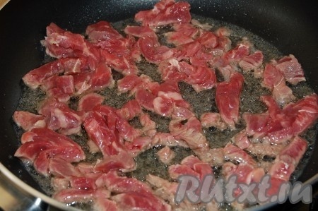 Растопим сливочное масло. Нарежем говядину тонкими брусочками и отправим жариться на сковородку. Обжариваем говядину на среднем огне в течение 7-10 минут, периодически помешивая.