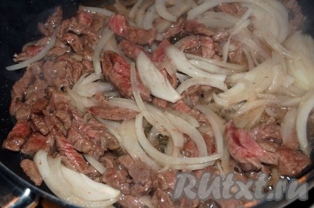 Отправляем лук к обжаренной говядине и готовим на среднем огне, перемешивая время от времени, до прозрачности лука.
