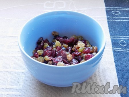 Изюм и вяленую клюкву промыть, залить кипятком и оставить на 30 минут. Затем откинуть на сито, слить воду. Выложить на бумажное полотенце и обсушить.
