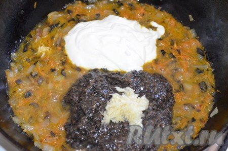 Чеснок очистить. В небольшой ёмкости соединить сметану и муку, тщательно перемешать. Когда морковка станет мягкой, добавить в сковороду измельчённые в блендере грибы, нарезанный (или пропущенный через пресс) чеснок и сметану, смешанную с мукой. 