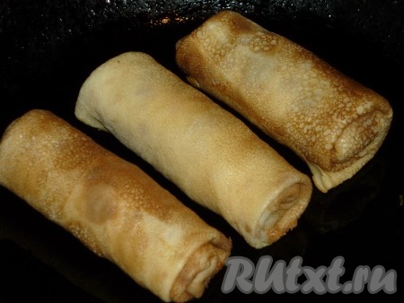 С помощью кисточки слегка смазать сковороду растительным маслом. Выложить блины начинкой из куриной печени на сковородку швом вниз и обжарить до румяной корочки с одной стороны.
