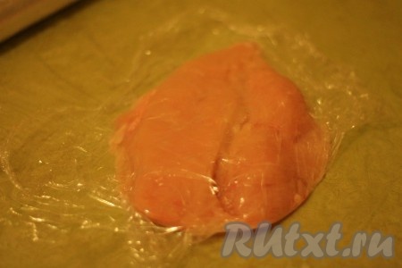 Куриное филе раскрыть, как книгу, положить между двумя слоями пищевой пленки.