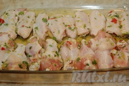 Взять форму, налить оливкового масла и выложить в нее крылышки.