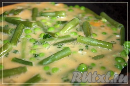 На сухую сковороду выложить стручковую фасоль с горошком и залить яйцами с луком. Жарить омлет до готовности под крышкой.
