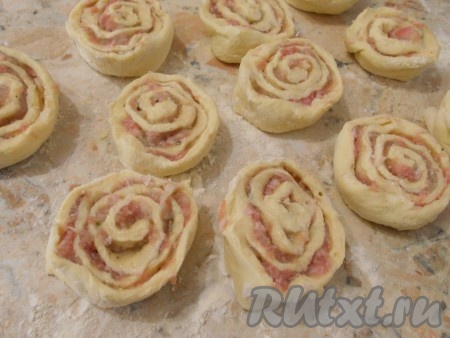 Плотно свернуть тесто в рулеты. Порезать их на части шириной 2-3 см (шире резать не рекомендую, шанежки плохо будут пропекаться). Тесто с фаршем слипается, поэтому каждый кусочек как бы развернуть руками, чтобы было похоже на розочку.
