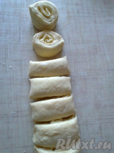 Скручиваем тесто в рулет, начиная с длинной стороны, и нарезаем на рулетики толщиной 2 сантиметра.