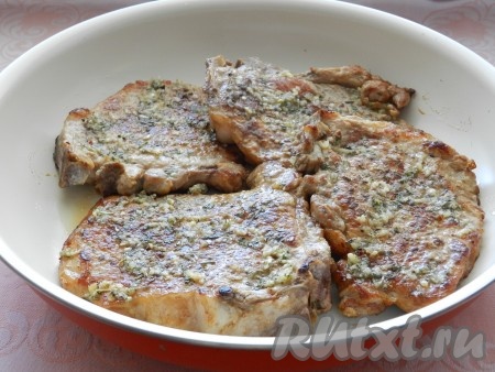 Обжаренные отбивные на косточке выложить в форму для запекания (я оставила в той же сковороде, она пригодна для запекания), каждую отбивную смазать приготовленным чесночным соусом. Накрыть форму фольгой и поставить в нагретую до 200 градусов духовку на 15-20 минут. Фольгу не снимать. За это время отбивные дойдут до готовности.
