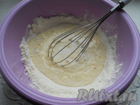 Отдельно смешать молоко с кипячёной водой. Получившуюся смесь из молока и воды частями вливать в углубление в мучной смеси, замешивая венчиком тесто.