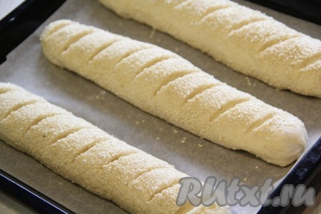 Противень для выпечки застелить пергаментной бумагой. Выложить багеты на застеленный противень на расстоянии друг от друга. С помощью острого ножа или лезвия сделать надрезы на поверхности. Поставить багеты в тепло на 30 минут для расстойки. Затем отправить противень с багетами с кунжутом в разогретую духовку и выпекать минут 25 (до золотистого цвета) при температуре 200 градусов.