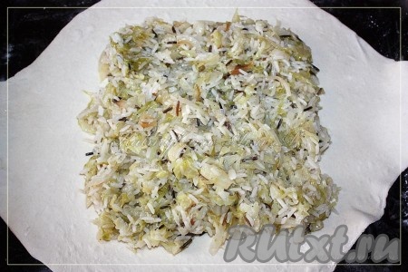 Готовое слоеное тесто разморозить и раскатать достаточно тонко, выложить пласт раскатанного теста на присыпанный мукой противень, на середину положить начинку.
