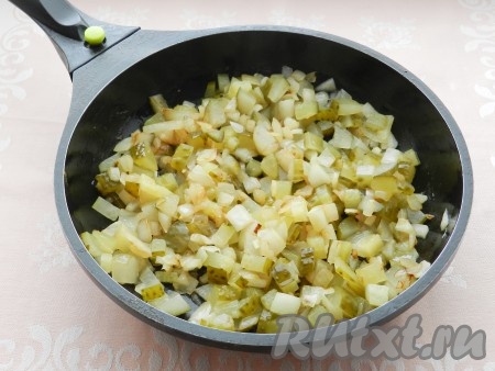 Пока тушится говядина, в отдельной сковороде нагреть немного растительного масла, выложить лук и обжарить его на среднем огне до мягкости (на это потребуется 4-5 минут), иногда помешивая. К обжаренному луку добавить огурцы, перемешать, прогреть на небольшом огне минуты 2, иногда помешивая.