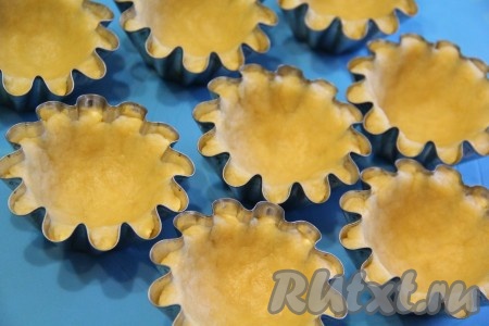 Из песочного теста сформировать небольшой шарик, выложить его на дно формы и хорошо распределить тесто по всей формочке. Сформировать высокий бортик. Не делайте корзиночки слишком тонкими, иначе потом вам будет трудно извлечь их из формочки.