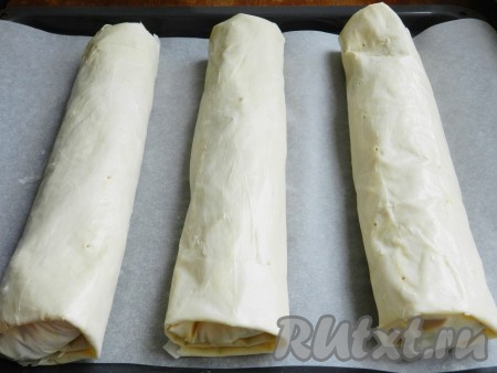 Сформированный рулет из теста фило с яблоками выложить на противень, застеленный пергаментом. Аналогично сформировать и выложить на застеленный противень ещё 2 рулета. Сверху рулеты смазать сливочным маслом. При помощи зубочистки сделать несколько проколов на каждом рулете, чтобы в процессе выпечки пар из начинки не разорвал тесто.