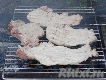 Жарить антрекоты из свинины на мангале над раскалёнными углями (прямого огня быть не должно) до готовности (примерно, по 8-10 минут с каждой стороны).