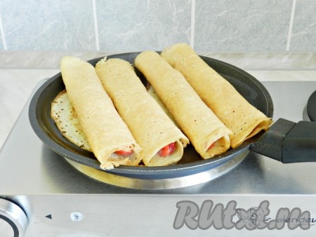 В сковороде разогреть немного сливочного масла и прогреть блинчики с одной стороны в течение 2 минут.
