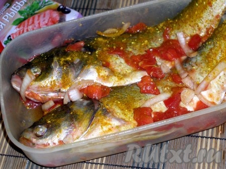 Почистить рыбу, плавники обрезать, жабры удалить, тщательно промыть. Провести внутри рыбки ручкой ножа по хребту, чтобы вышла вся жидкость, ещё раз промыть. Рыбу поместить в ёмкость, посыпать специями, обложить помидорами, нарезанными на кусочки, и кольцами лука, обмазать этой смесью голову и брюшко рыбы. Не забудьте внимательно ознакомиться с составом специй, если соль не входит в их состав, то рыбу нужно посолить (примерно 1 чайная ложка без горки соли). Оставить мариноваться не менее чем на 20 минут. Я оставляла рыбу мариноваться до вечера, так как готовила её на ужин.