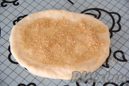 Каждый кусочек теста раскатать в нетонкий овал. Смазать поверхность теста растопленным сливочным маслом, а затем, немного отступив от краёв, присыпать 1 чайной ложкой сахара (я использовала тростниковый сахар).