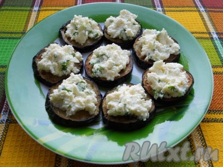 Выложить кружочки баклажанов на тарелку или блюдо, сверху на каждый кружочек положить по ложке сырной массы.
