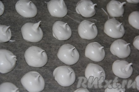 Переложить белковую массу в кондитерский мешок с круглой насадкой. Если у вас нет кондитерского мешка, то можно сформировать безе с помощью ложки. Противень для выпекания застелить пергаментной бумагой. Отсадить белковую массу на противень на расстоянии друг от друга. Безе можно отправлять в духовку и в таком виде, но чтобы сделать вкус более интересным, можно украсить каждую безешку миндалем.