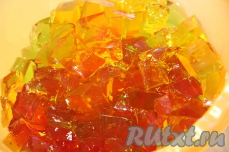 Перед нарезанием желе смочить нож под горячей водой. Нарезать цветное желе на кубики. Кубики должны быть среднего размера. Выложить кубики разных цветов в миску и аккуратно перемешать.
