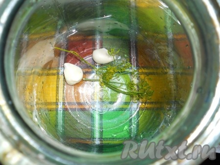 На дно чистых банок поместить по 1 зубчику чеснока, разрезанного на 2 части, и по зонтику укропа.
