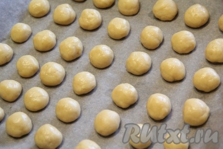 Противень для выпекания застелить пергаментной бумагой. Из теста сформировать шарики, размером, примерно, с большой грецкий орех. Я просто отщипывала от основной массы теста небольшие кусочки и скатывала их в шарики, как на фото. Выложить получившиеся шарики на противень, застеленный бумагой для выпечки.
