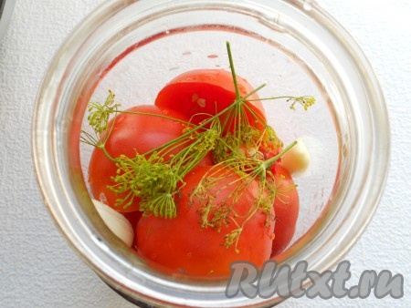 Помидоры вымыть, разрезать пополам, удаляя место крепления плодоножки. Наполнить банку половинками помидоров, выкладывая их срезом вниз. Между помидорами поместить по зубчику чеснока, кружочку горького перца и зонтику укропа.