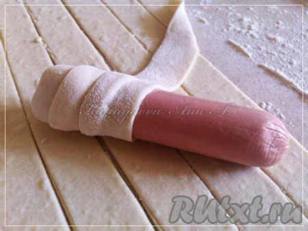 Замотать сосиски полоской теста по спирали, как на фото.
