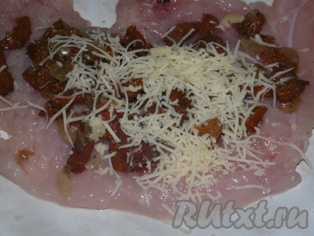 20 грамм сыра натереть на мелкой тёрке. Лисички, жареные с луком, зрительно разделить на 4 части (по количеству куриного филе). На каждый кусочек отбитого куриного филе выложить одну часть лисичек с луком, посыпать 1/4 частью натёртого сыра. Аккуратно свернуть каждое филе в рулетик так, чтобы начинка была внутри, и положить в форму для запекания.