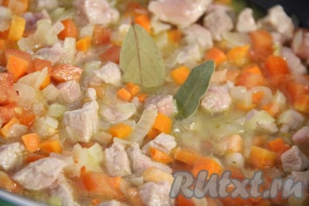 Посолить и поперчить по вкусу содержимое сковороды, влить 250 миллилитров горячей воды, добавить лавровые листья, перемешать, тушить свинину с овощами с момента закипания под крышкой на небольшом огне 10 минут.